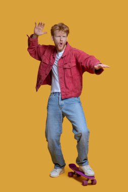 Kırmızı ceketli, kendine güveni tam, kaykaylı genç adam.