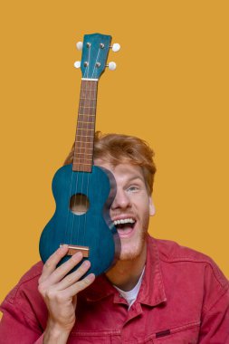 Kırmızı ceketli, sakallı yakışıklı genç adam eğleniyor.