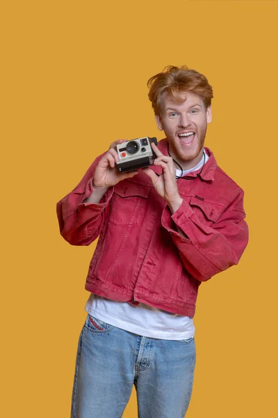 Рудий бородатий молодий чоловік зі старою камерою відчуває себе щасливим — стокове фото