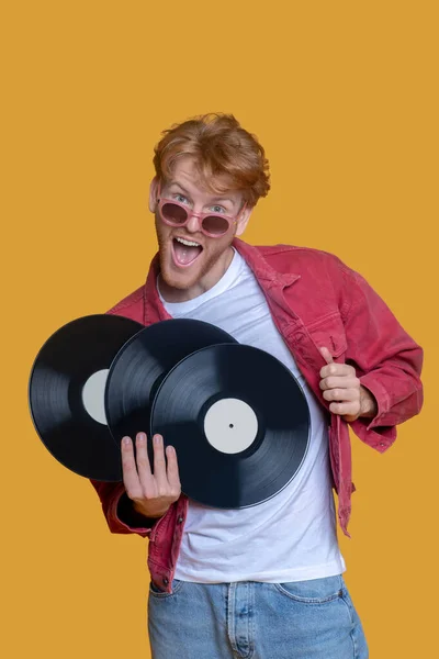 Red-haired bearded young man in red glasses with records — Stock Photo, Image