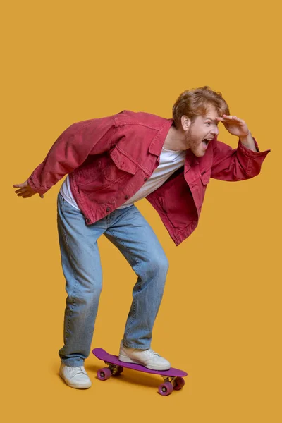 Ingefära ung man i röd jacka med en skateboard — Stockfoto