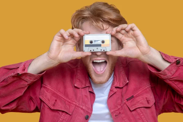 Jonge gember man in rode jas met een cassette — Stockfoto