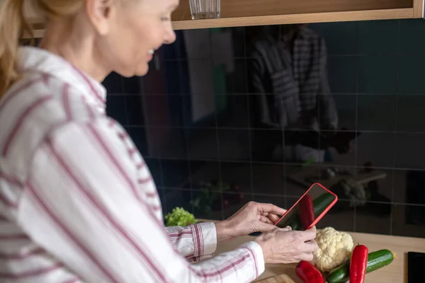 Mujer de pie en la cocina y buscando recetas en línea — Foto de Stock