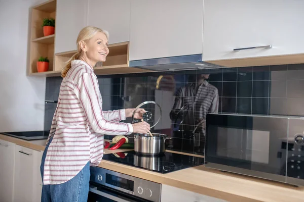 Жінка стоїть біля плити на кухні — стокове фото