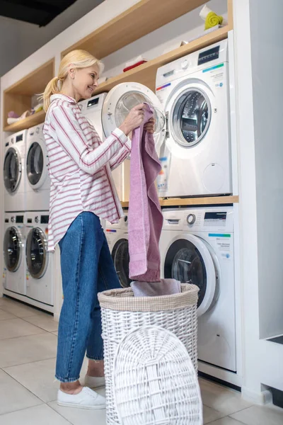 Mujer rubia con camisa a rayas sacando la ropa de la cesta — Foto de Stock