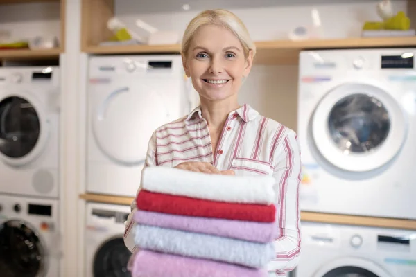 Sorridente donna bionda in possesso di un mucchio di asciugamani — Foto Stock