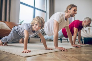 İki adam ve oğulları tahtanın üzerinde duruyorlar.