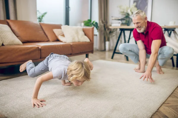 Hombre de pelo gris en forma haciendo yoga junto con su hijo —  Fotos de Stock