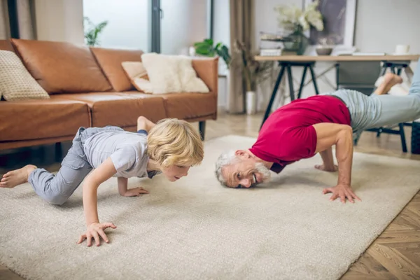 Bell'uomo in forma che fa yoga con suo figlio — Foto Stock