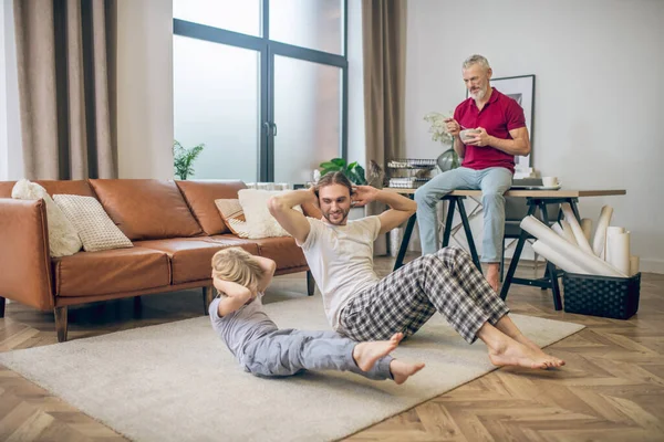 Familia haciendo ejercicios en casa y sintiéndose bien — Foto de Stock