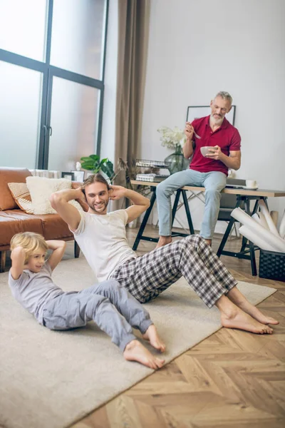 Familia haciendo ejercicios en casa y sintiéndose bien —  Fotos de Stock