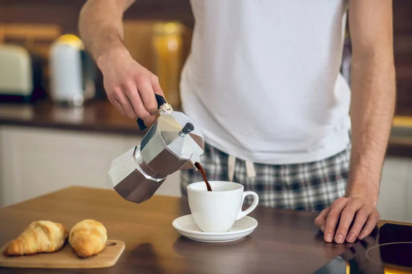 Close up of man in homewear pouring coffee to the cup — Stock Photo, Image