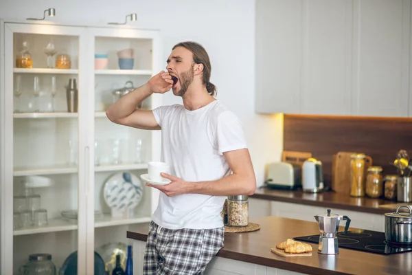 Jongeman in huiskleding die koffie drinkt in de keuken — Stockfoto