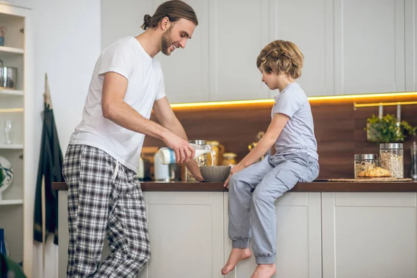 Joven en ropa de casa y su hijo desayunando —  Fotos de Stock