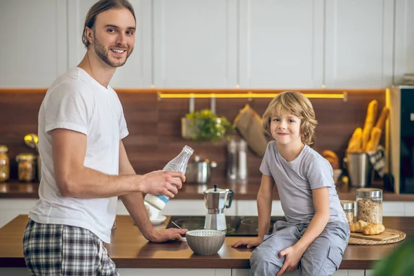 Junger Mann in Hauskleidung und sein Sohn frühstücken — Stockfoto