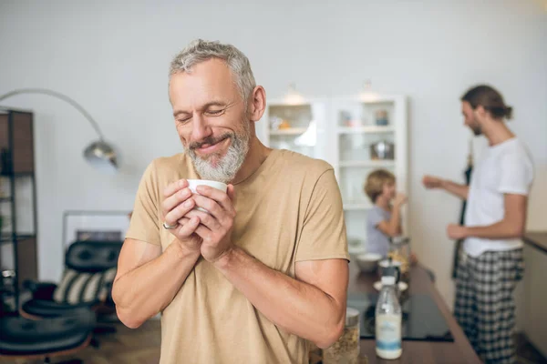Hombre de pelo gris tomando café por la mañana y sintiéndose bien — Foto de Stock