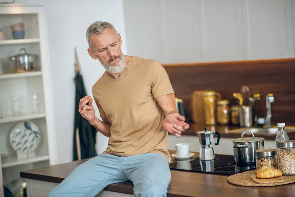 Maturo uomo in beige tshirt in cucina giocare aria chitarra — Foto Stock