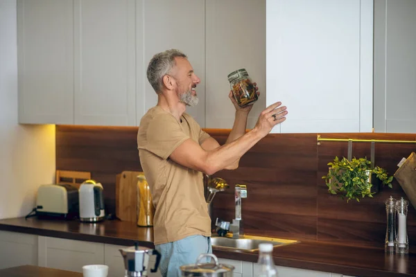 Volwassen man met baard in beige tshirt in de keuken thuis — Stockfoto