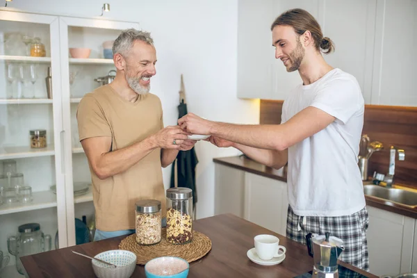 Lächelndes Paar frühstückt gemeinsam zu Hause und fühlt sich wohl — Stockfoto