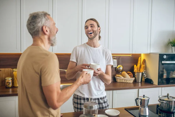 Lächelndes Paar frühstückt gemeinsam zu Hause und fühlt sich wohl — Stockfoto