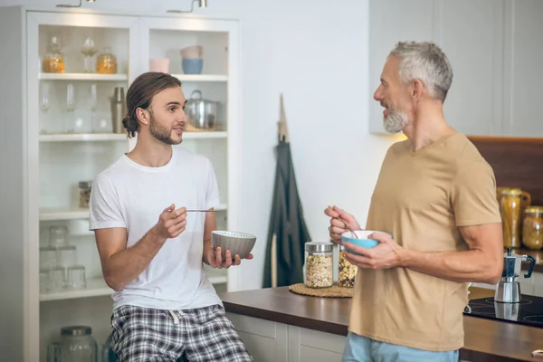 Smiling couple having coffee and talking in the kitchen — Stock Photo, Image