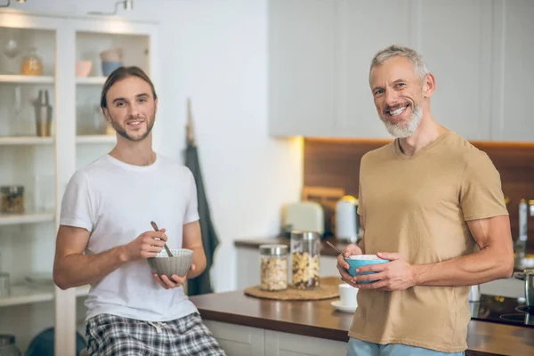 Sonriente pareja de pie en la cocina y mirando feliz — Foto de Stock