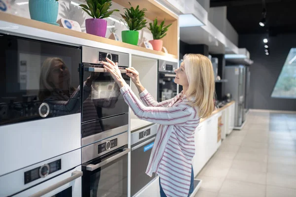 Blond kund väljer ugn i ett showroom — Stockfoto