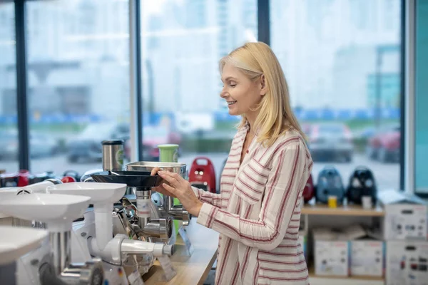 Blonde femme client debout dans une salle d'exposition de biens de consommation et de choisir une machine à hacher — Photo