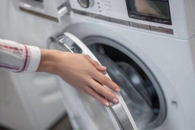 Kadın elinin çamaşır makinesini incelerken çekilmiş bir fotoğrafı kapat.