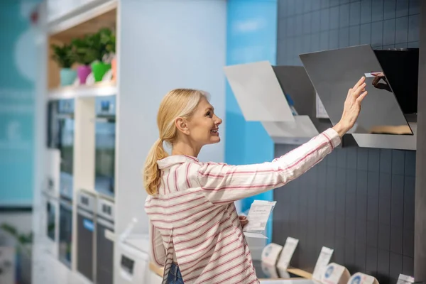 Mujer rubia de mediana edad eligiendo productos en una sala de exposición — Foto de Stock