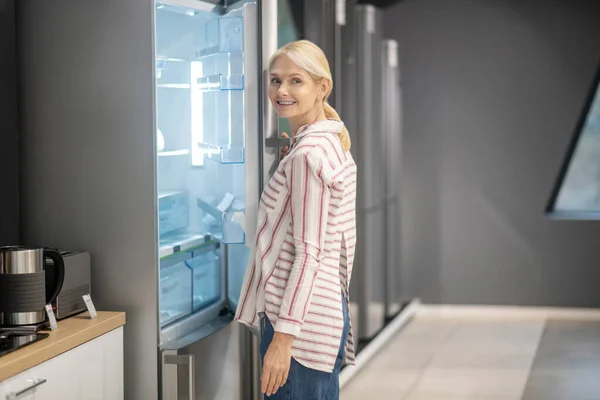 Blondynka kobieta klient wybierając lodówkę w megastore — Zdjęcie stockowe