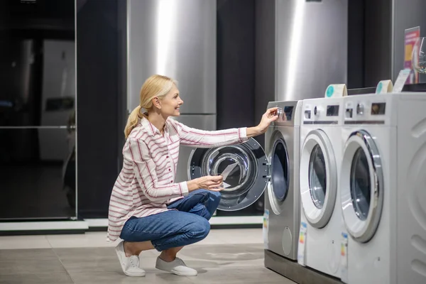 Cliente femenino en camisa a rayas eligiendo una lavadora en megastore —  Fotos de Stock