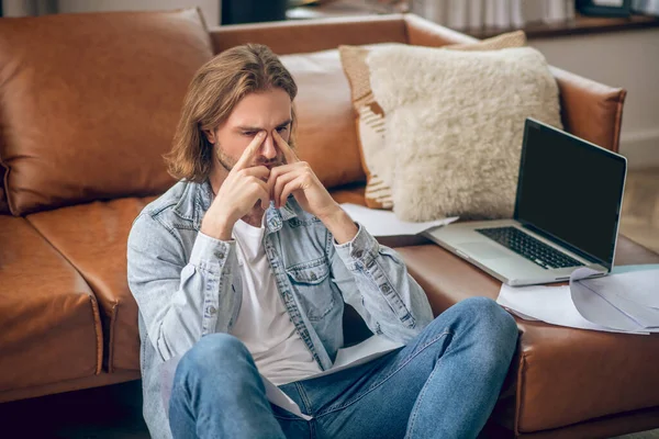 Joven tipo en jeans camisa sosteniendo papeles y buscando reflexivo — Foto de Stock