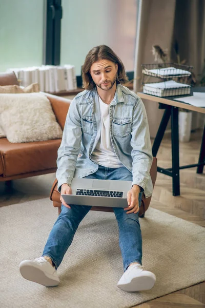 Mann in Jeanshemd arbeitet am Laptop und sieht verwirrt aus — Stockfoto
