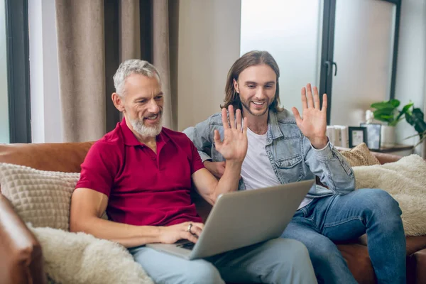 Två män som sitter bredvid varandra och har ett videosamtal — Stockfoto