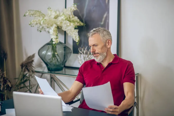 Homme aux cheveux gris travaillant avec des papiers et ayant l'air sérieux — Photo