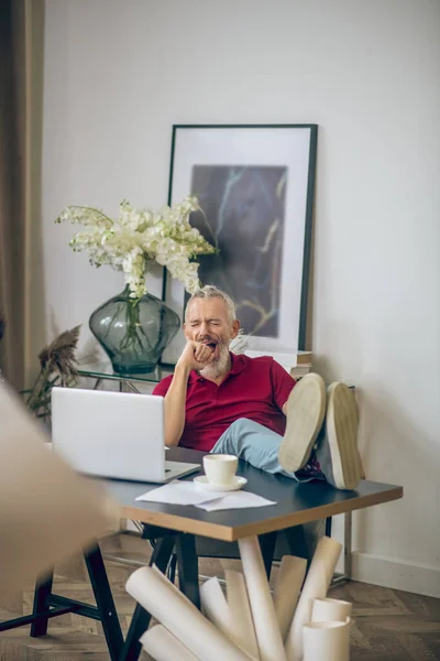 Hombre de pelo gris sentado en el portátil y mirando aburrido —  Fotos de Stock