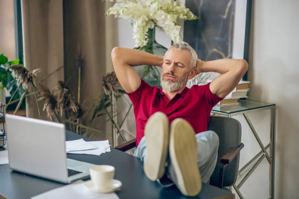 Homme aux cheveux gris assis à l'ordinateur portable et l'air ennuyé — Photo