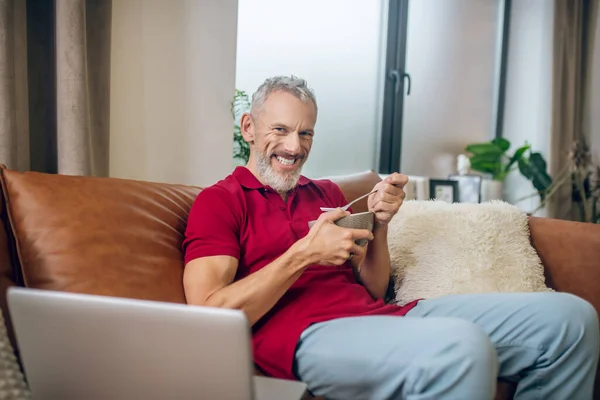 Grauhaariger Mann beim Mittagessen und beim Ansehen eines Videos — Stockfoto