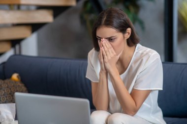 Laptopuyla çalışan üzgün ve konsantre bir kadın.