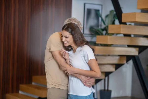 Reifer Mann und junge Frau, die sich umarmen und verliebt aussehen — Stockfoto