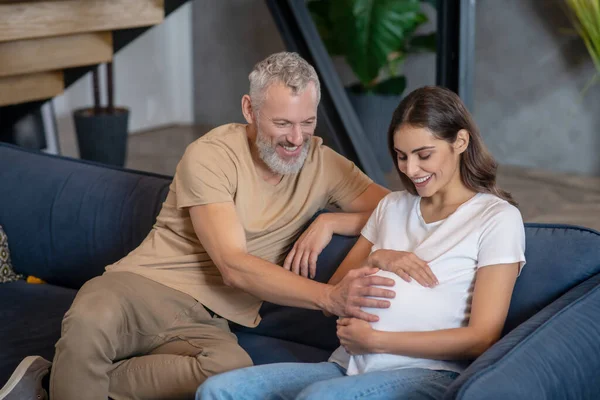 Glücklich reifer Mann und junge schwangere Frau sitzen und reden — Stockfoto