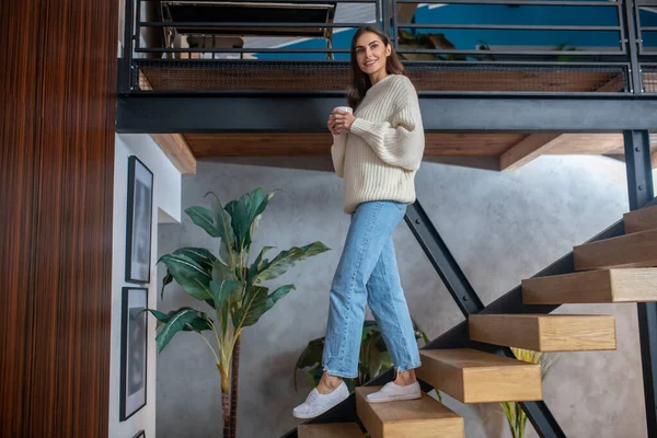 Jonge donkerharige mooie vrouw in jeans en witte trui thuis — Stockfoto