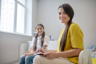 Neşeli gülümseyen kız ve genç kadın psikolog.