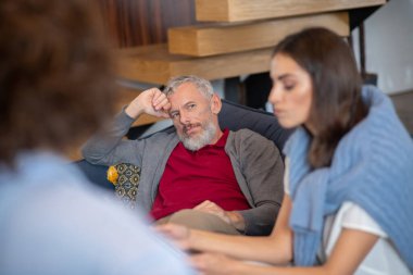 Terapi seansı boyunca karısına tepeden bakan bir adam.