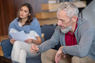 Gri saçlı adam evlilik yüzüğüne bakıyor.