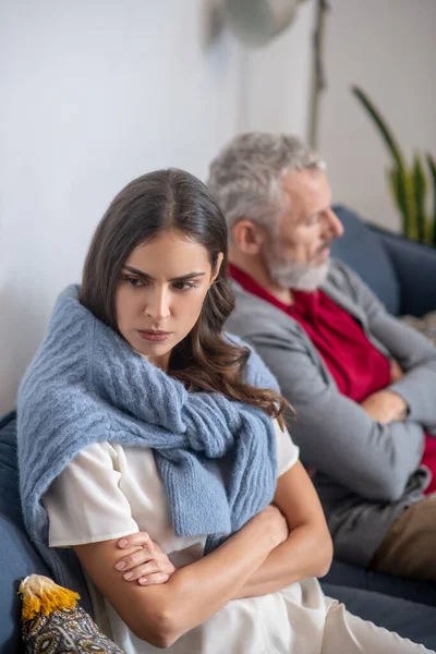 Раздраженная женщина, сидящая на диване рядом с мужем — стоковое фото