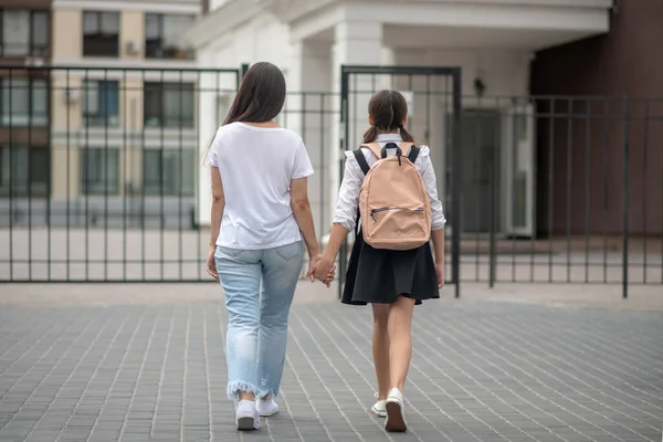 Mulher com colegial andando de braço em braço para a escola — Fotografia de Stock