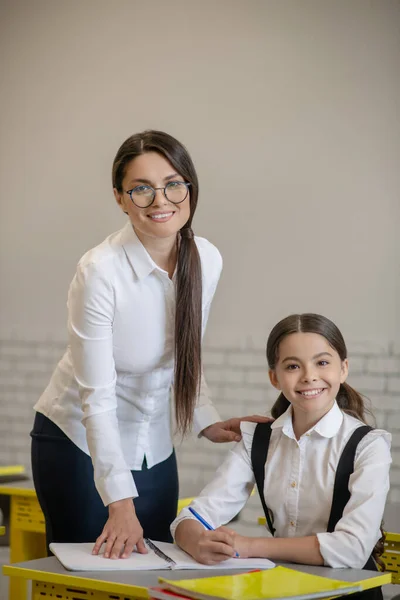 Smiling teacher and her schoolgirl in class — Stock Photo, Image