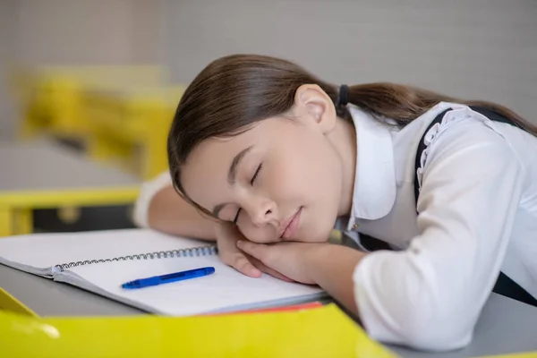 Schoolgirl with closed eyes resting head on desk — Stock Photo, Image